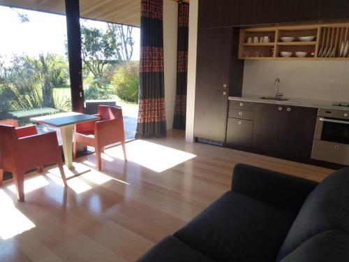 Una sala de estar con mesa y sillas y una cocina. en Hot Water Beach Bure Wera, en Hotwater Beach