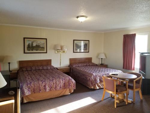 a hotel room with two beds and a table at Sooner Motel in Stroud