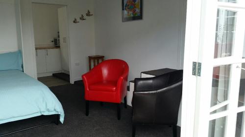 a bedroom with a red chair and a bed at Mauao Studio in Mount Maunganui