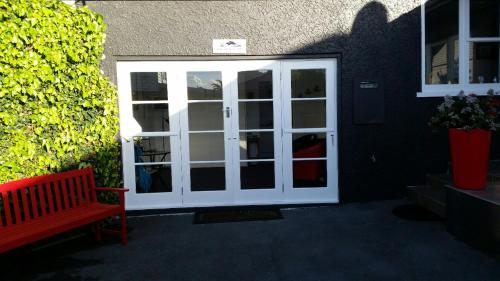 a white door with a red bench in front of a building at Mauao Studio in Mount Maunganui