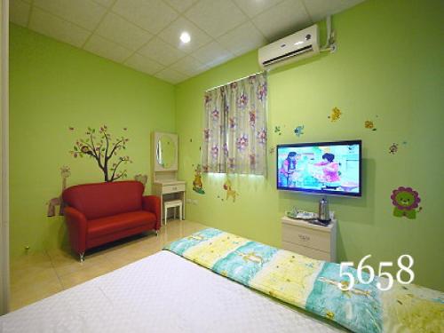 a bedroom with a bed and a tv and a red chair at Hua Qiao De Jia in Donggang