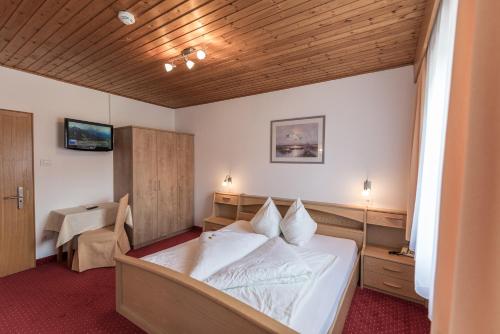 una camera con un grande letto e un soffitto in legno di Hotel B&B Feldmessner a Brunico