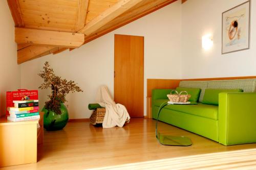 a living room with a green couch and a table at Millenniumshof in Caldaro