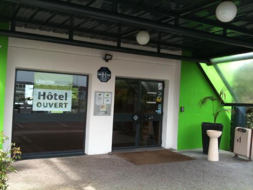 a hotel entrance with a green and white building at Lemon Hotel - Tourcoing in Tourcoing