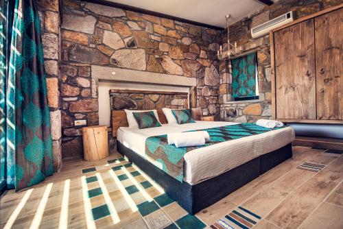 a bedroom with a bed in a stone wall at Keros Blue - Luxury in Wilderness in Kalliópi