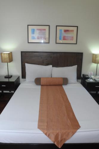a large white bed in a room with two lamps at El Cielito Hotel - Baguio in Baguio