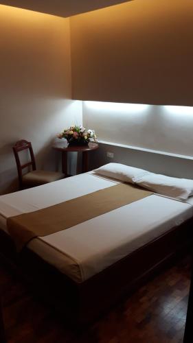 a bedroom with a bed and a table with a chair at El Cielito Hotel - Baguio in Baguio