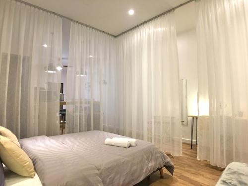 a bedroom with white curtains and a bed with two towels at iBook Gurney Suites in George Town