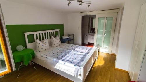 1 dormitorio con cama blanca y pared verde en Rauhbergerhof, en Tiefgraben