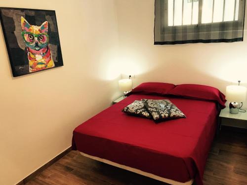 a bedroom with a red bed with a cat painting on the wall at Apartments Las Floritas in Playa de las Americas