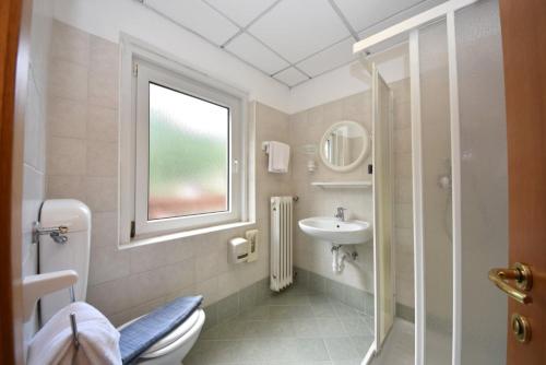 łazienka z toaletą, umywalką i oknem w obiekcie Hotel Villa Agomer w mieście Canazei