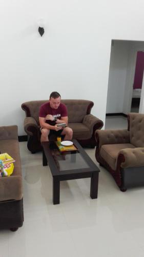 a man sitting on a couch in a living room at Ahasna Airport Villa in Negombo