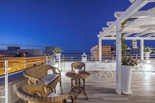 a balcony with chairs and tables on a roof at Muragie del Castello B&B in Trani