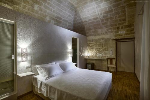 トラーニにあるMuragie del Castello B&Bのレンガの壁のベッドルーム1室(白いベッド1台付)
