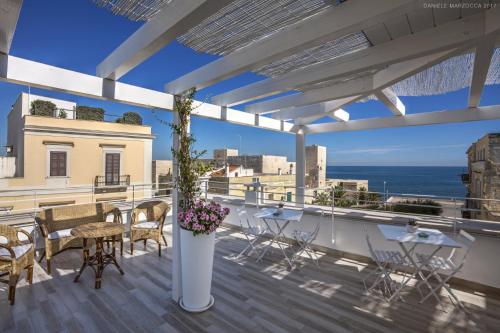 a balcony with tables and chairs and a view of the ocean at Muragie del Castello B&B in Trani