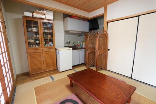 a kitchen with a wooden table in a room at Guesthouse Hikari in Kumano