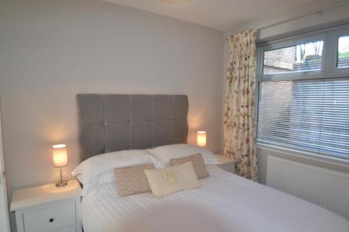 a bedroom with a white bed with two lamps and a window at Charming 1 bed riverside apartment in Chester