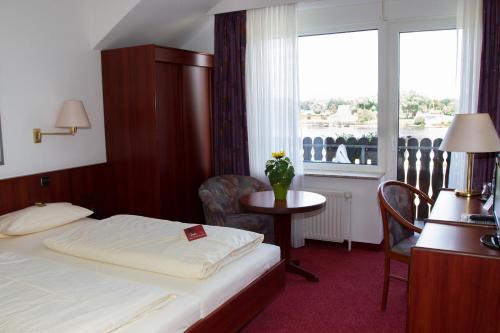 a hotel room with a bed and a table and a window at Hotel Seeblick garni in Gartow