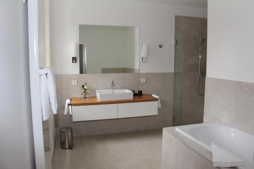 ein Badezimmer mit einem Waschbecken, einer Badewanne und einem Spiegel in der Unterkunft Hotel Schloss Dyck in Jüchen