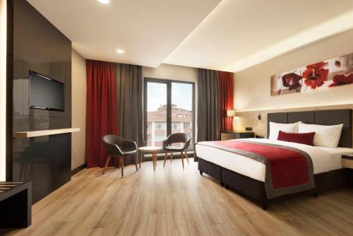 ゲブゼにあるRamada Encore Gebzeのベッドとテレビが備わるホテルルームです。