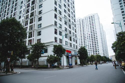 a white building on a street with tall buildings at Full House Times City in Hanoi