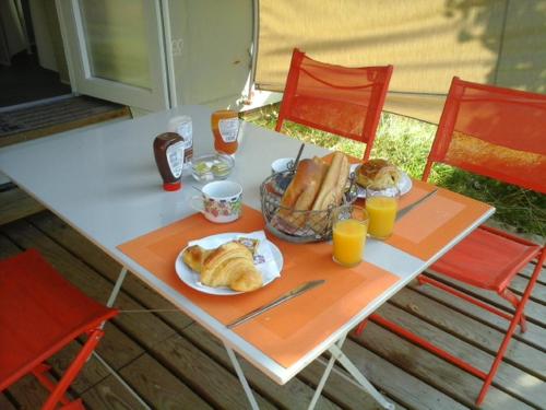 ein Tisch mit einem Teller Essen und Orangensaft in der Unterkunft Camping les Tournesols in Sillé-le-Guillaume