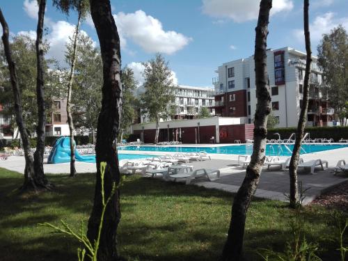 Una piscina con sillas y un edificio. en Apartament Morskie Polanki, en Kołobrzeg