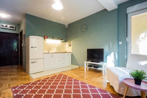 a living room with a white refrigerator and a tv at ! PROMO! Central Evergreen Studio - Free Public Parking-Fast WI-FI in Novi Sad