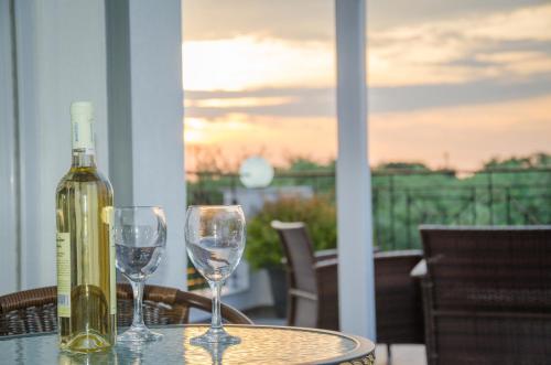 a bottle of wine sitting on a table with two wine glasses at Olivera Apartments in Skala Rachoniou