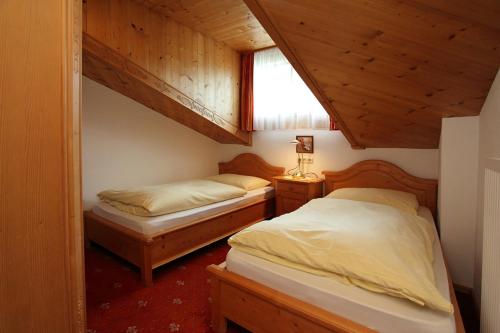 two beds in a room with wooden walls and ceilings at Appartements Wirnsperger in Grossarl