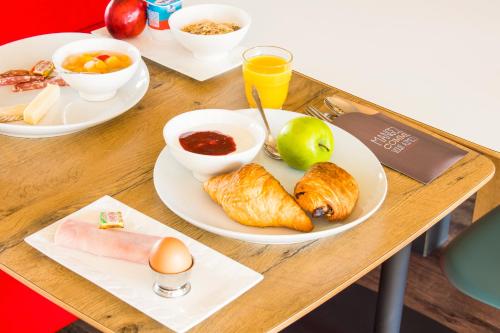 a wooden table with plates of food on it at ibis Nemours in Nemours