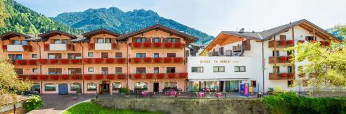 un hôtel dans les montagnes avec des tables et des chaises dans l'établissement Family Hotel La Perla, à Fiera di Primiero