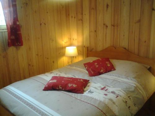 a bedroom with a bed with two red pillows at Le chalet in Briançon