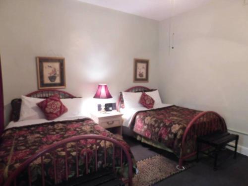 a hotel room with two beds and a table with a lamp at Cassadaga Hotel and Spiritual Center in Cassadaga