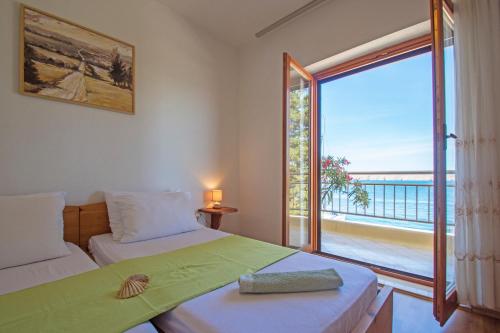 a bedroom with two beds and a large window at Apartmani Viktorija in Jadranovo