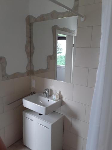 een witte badkamer met een wastafel en een spiegel bij Pöhl am Nationalpark Eifel in Schleiden