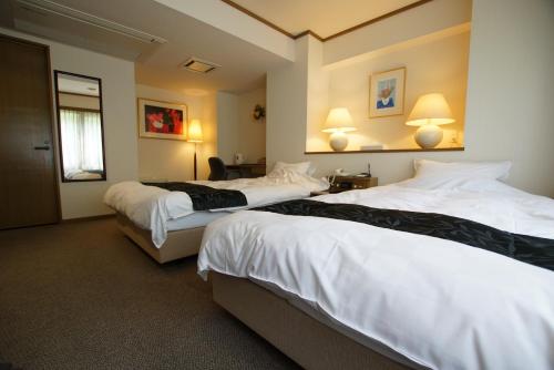 pokój hotelowy z 2 łóżkami i 2 lampami w obiekcie Suizansou w mieście Toyooka