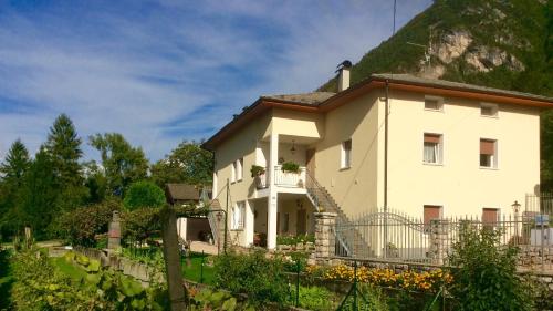 Una gran casa blanca con una colina detrás. en Casa Roberto - piano terra con giardino, en Levico Terme