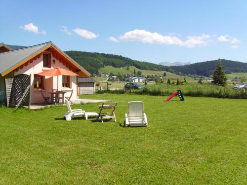 um quintal com duas cadeiras e uma mesa e um parque infantil em Gite Waykiu em Autrans