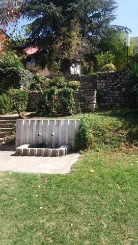 a stone wall with a bench in a yard at Vila Popovski in Ljubaništa