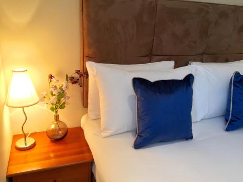 a bed with blue and white pillows and a lamp at Rochester Apartment in London