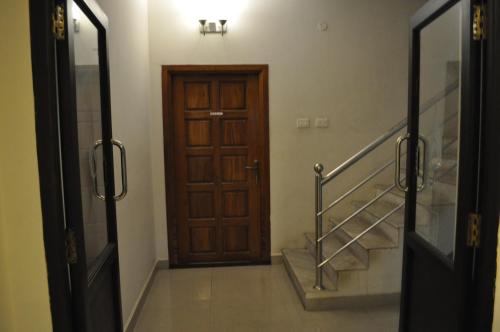 a hallway with a wooden door and a staircase at Jyothi Suites in Srīrangam