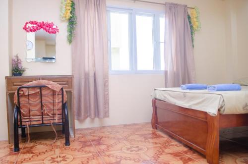 a bedroom with a bed and a desk and a window at Julz Tropical Apartments in Olongapo