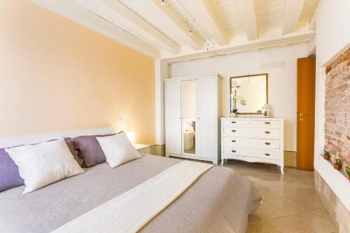 um quarto com uma cama e uma cómoda com um espelho em Cà Biennale, respirare la Venezia autentica! 0-27042-LOC-13975 Z07763 em Veneza