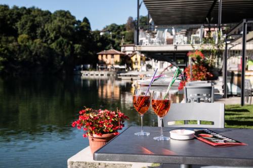 two glasses of wine sitting on a table next to a river at Hotel Due Palme in Mergozzo