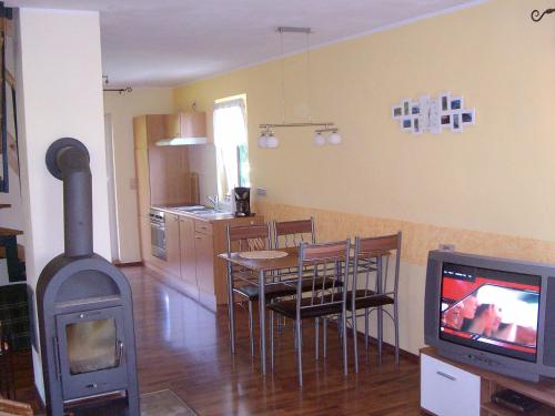 a living room with a stove and a table and a television at Ferienhaus Henke in Hohnstein