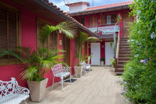 una casa roja con sillas blancas y plantas en un porche en Pousada Praia e Conforto, en Búzios