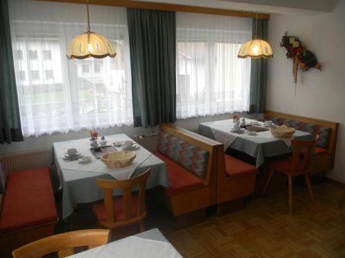 a dining room with two tables and chairs and windows at Haus Zentner in Nauders
