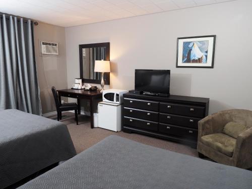 um quarto de hotel com uma cama, uma secretária e uma televisão em Ambassador Motel em Sault Ste. Marie