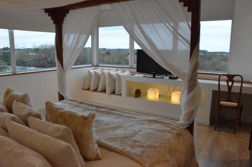 a bedroom with a canopy bed with a large window at Los Muelles Boutique Hotel in Carmelo